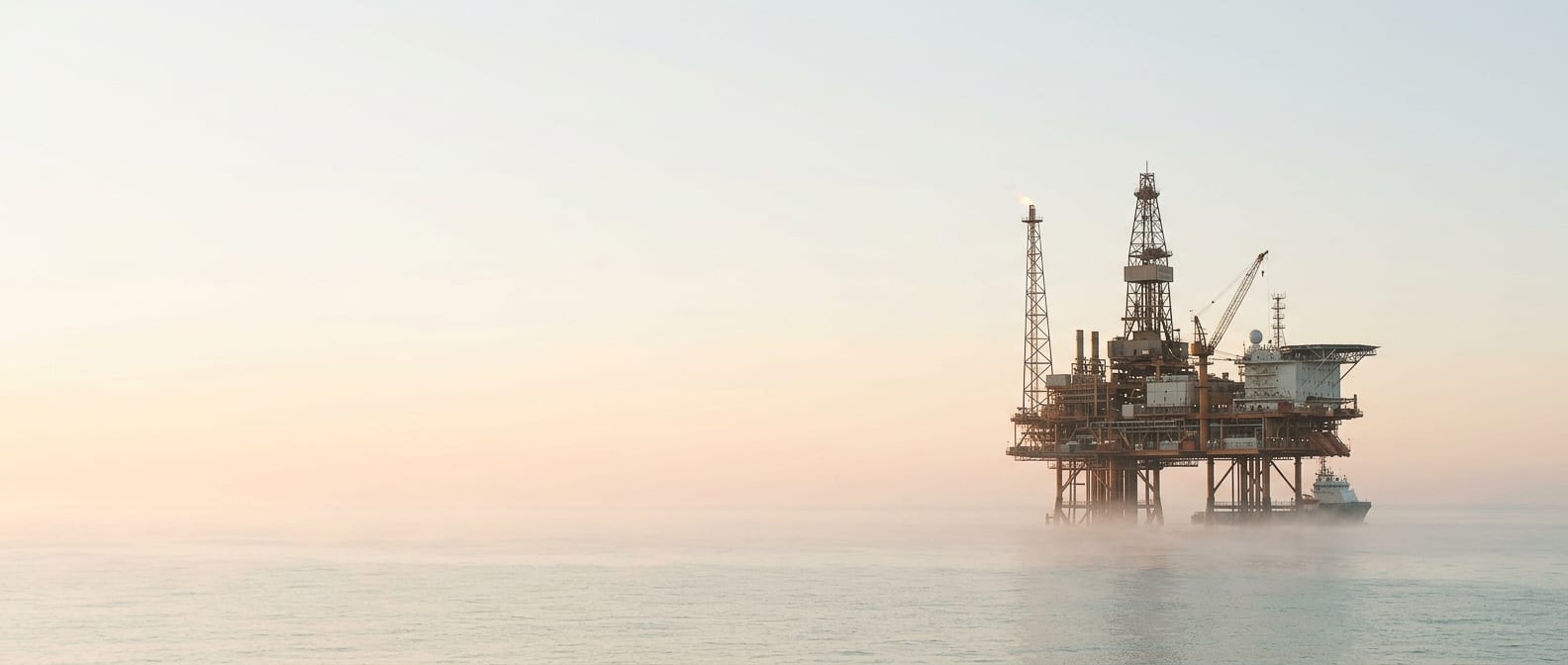 An offshore platform emerging from dawn mist, operational and real